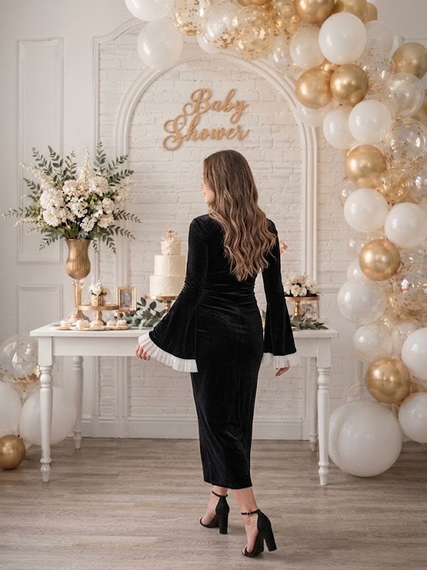 Back view of black velvet maternity midi dress with ruffled mock neck and bell sleeves, designed for baby shower.